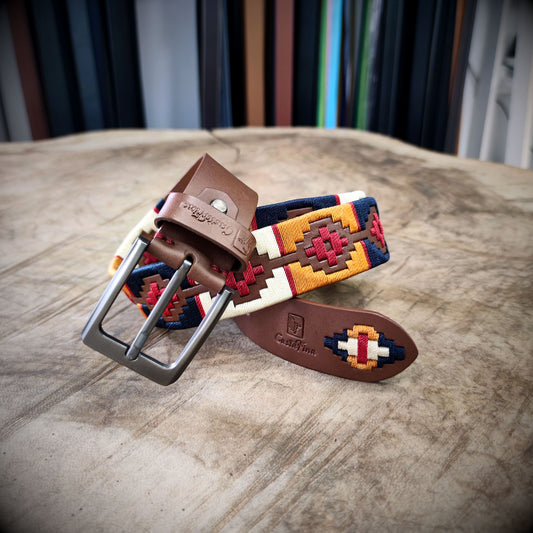 VALENTÍA – Tradición con Firmeza | Cuero caramelo con tejido en rojo, mostaza, azul oscuro y beige – Cinturón tejido CASTAFINA Platino (Ref. TC-065)