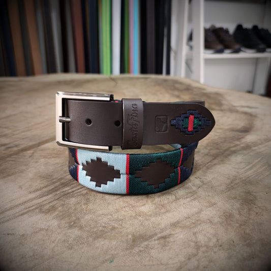 MONTAÑA – Fuerza que Inspira Respeto | Cuero chocolate con tejido en verde pino, azul oscuro, celeste y detalles rojo intenso – Cinturón tejido CASTAFINA clásico (Ref. TC-063)